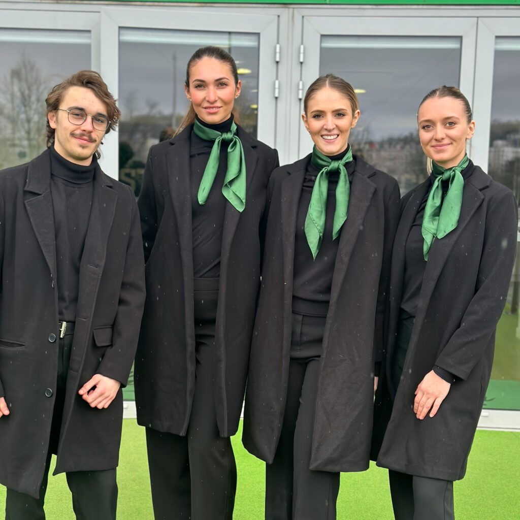 Équipe d’hôtes et d’hôtesses Crown Agency en tenue noire et foulard vert, accueillant et orientant des invités dans les loges du Stade Geoffroy-Guichard lors d’un événement avec animations et quiz.